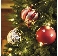 Drei Christbaumkugeln an einem Weihnachtsbaum mit Beleuchtung.