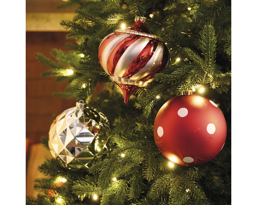 Drei Christbaumkugeln an einem Weihnachtsbaum mit Beleuchtung.