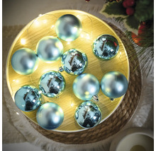 Dekorative, blaue Weihnachtskugeln mit Lichterkette auf einem Teller