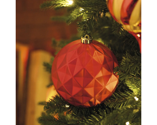 Nahaufnahme eines roten, facettierten Weihnachtsbaumschmuckes an einem Weihnachtsbaum