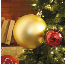 Nahaufnahme eines Weihnachtsbaums mit goldenen und roten Christbaumkugeln und Lichtern