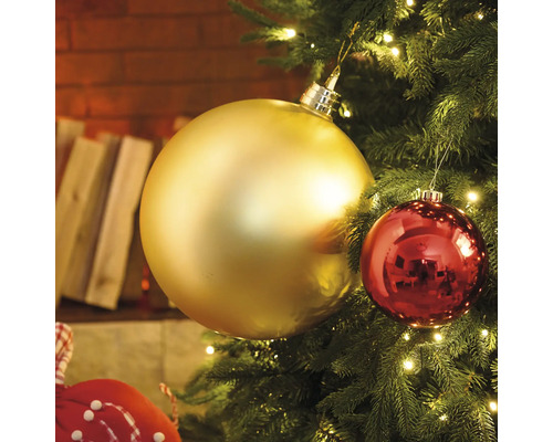 Nahaufnahme eines Weihnachtsbaums mit goldenen und roten Christbaumkugeln und Lichtern