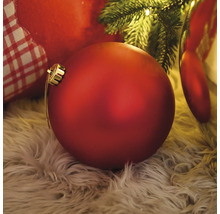 Dekorativer, roter Weihnachtsbaumschmuck auf einem Fellteppich