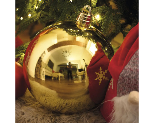 Goldene Christbaumkugel mit Aufhänger vor Weihnachtsbaum