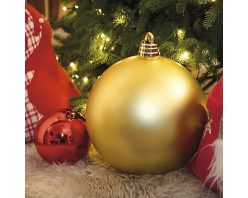 Goldfarbene und rote Christbaumkugeln unter einem Christbaum