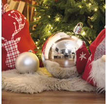 Dekorative Weihnachtskugeln unter einem beleuchteten Weihnachtsbaum mit Geschenksäcken auf einem Teppich