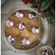 Anordnung von rosa Weihnachtskugeln auf einem Holzteller mit Tannenzweigen und Dekoration