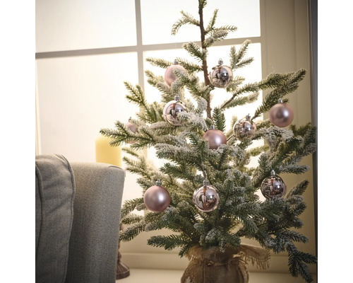 Dekorierter kleiner Weihnachtsbaum mit Christbaumkugeln vor einem Fenster