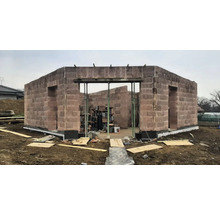 Rohbau eines Hauses aus Mauersteinen mit Türöffnungen und Baustützen