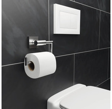Toilette mit Toilettenpapierhalter, Spültaste und dunklem Fliesenhintergrund