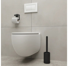 Wandhängendes WC mit Toilettenpapierhalter und Toilettenbürste in einem Badezimmer.