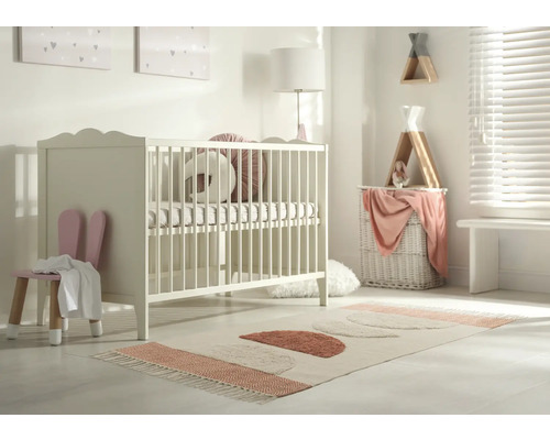 Kinderzimmer mit Gitterbett, Stuhl mit Hasenohren und Teppich mit geometrischen Formen.