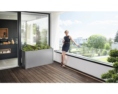 Balkonszene mit Pflanzgefäß, Frau und Kücheneinblick