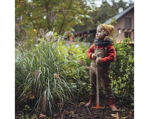 Kind mit Rechen im Garten