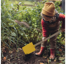 Kind mit gelbem Spaten gräbt im Garten