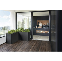 Balkon mit Holzboden und Pflanzenkübeln, Blick in moderne Küche mit Person