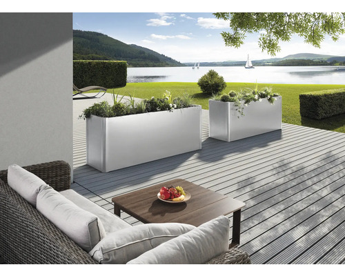 Dekorativer Gartenbereich mit Pflanzkästen, Sitzgruppe und Seeblick