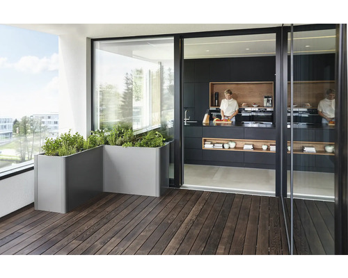 Balkon mit grauen Pflanzkästen und Blick in eine Küche mit schwarzer Küchenzeile