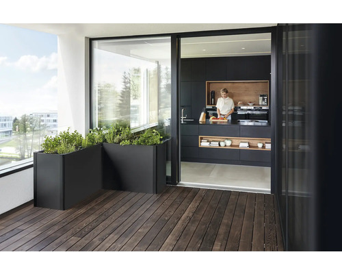 Terrasse mit Holzfußboden, Pflanzenkübeln und Blick in eine Küche