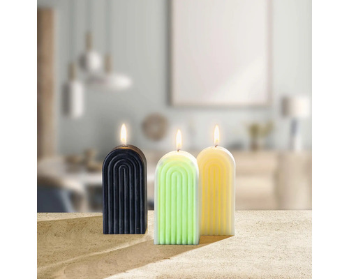 Drei dekorative Kerzen mit Bogenmuster stehen auf einem Tisch.