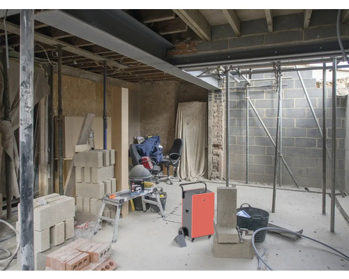 Innenraum im Rohbau mit Baumaterialien und Baugeräten