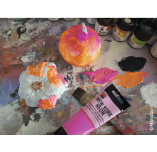 Bemalte Kürbisse mit Farben und Pinsel auf einer Arbeitsfläche.