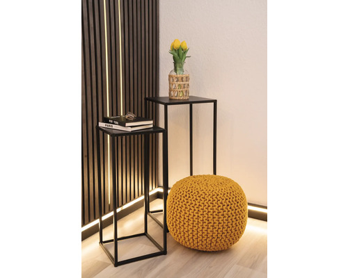 Zwei Beistelltische mit schwarzem Metallgestell, ein gelber Pouf und eine Vase mit gelben Tulpen