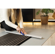 Frau schneidet Akustikpaneel mit Schneidwerkzeug auf Schneideunterlage