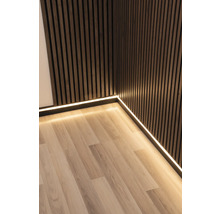 Zimmerecke mit Holzpaneelwand, Sockelleiste mit LED-Streifen und Laminatboden