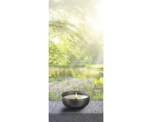 Brennende Duftkerze in einer Schale vor einem verschwommenen Gartenteich