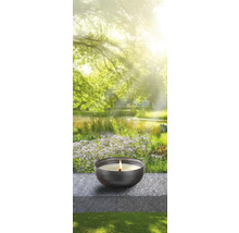 Kerze in einer Schale vor einem Gartenhintergrund