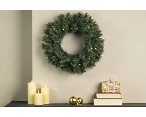Weihnachtliche Szene mit beleuchtetem Tannenkranz, Kerzen und Geschenk