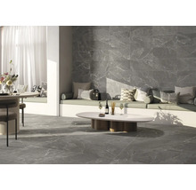 Wohnraum mit grauen Fliesen in Marmoroptik an Boden und Wand, Sitzbereich mit Kissen und Tisch