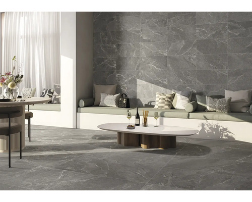 Wohnraum mit grauen Fliesen in Marmoroptik an Boden und Wand, Sitzbereich mit Kissen und Tisch