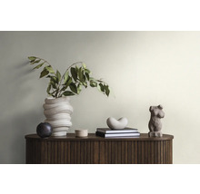 Dekorative Szene mit einer Blumenvase, Skulpturen und Büchern auf einem dunklen Holzschrank.