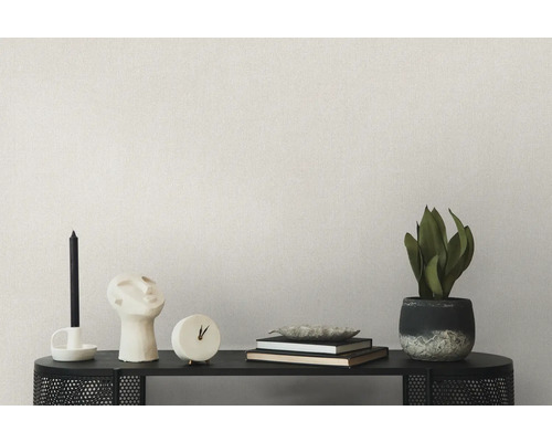 Wohnraumdekoration auf einem Regal mit Kerzen, Skulptur, Uhr, Büchern, Schale und Topfpflanze vor einer einfarbigen Wand