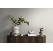 Dekorative Elemente auf einem Holzschrank mit Rillenstruktur: eine gewundene Vase mit Zweigen, eine kleine Kugel, eine Dose, Bücher, eine Herzform und eine weibliche Torsoskulptur.