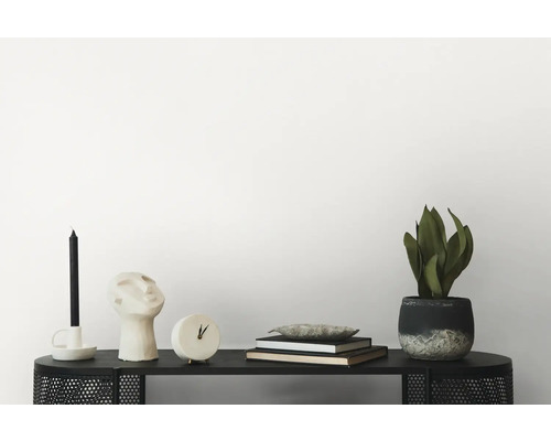 Dekorative Szene auf einem schwarzen Regal mit Kerze, Kopfskulptur, Uhr, Büchern und Zimmerpflanze.