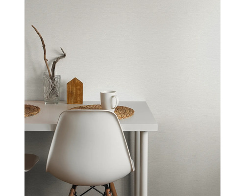 Szene mit weißer Tisch, Stuhl, Tasse und Dekoration vor einer strukturierten Tapete