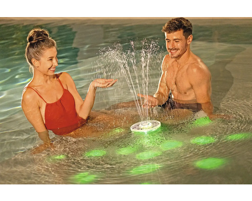 Ein Paar genießt einen schwimmenden Poolbrunnen mit Beleuchtung im Wasser.
