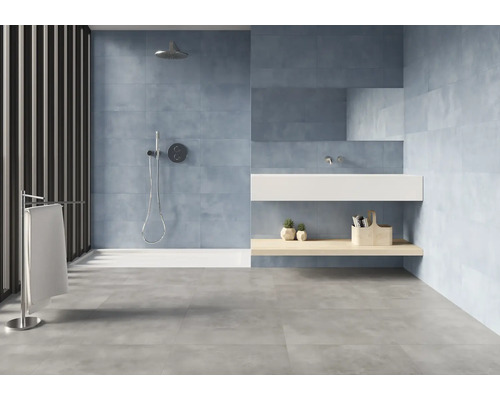 Helles Badezimmer mit Dusche, Waschbecken und grauen Bodenfliesen.