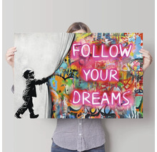 Wandbild mit der Aufschrift Folge deinen Träumen, eine Person hält das Bild hoch