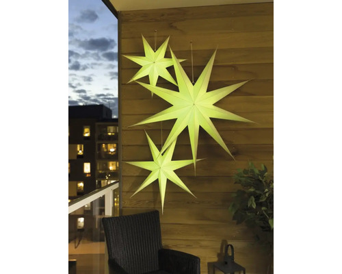 Dekorative Papiersterne hängen an einer Holzwand auf einem Balkon.