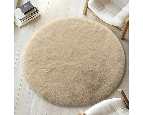 Runder, beiger Teppich auf hellem Holzboden, umgeben von Stühlen und Büchern.