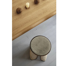 Ansicht von oben auf einen runden Hocker mit Fellbezug und einem Holztisch mit Dekoration
