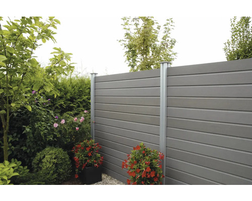 Gartenszene mit Zaun aus Kunststoffelementen und Metallpfosten, umgeben von Pflanzen