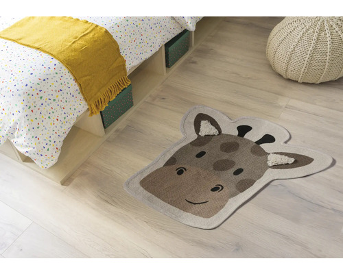 Zimmer Szene mit Bett, Sitzkissen und einem Teppich in Form eines Giraffenkopfes.