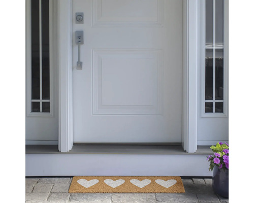 Fußmatte mit Herzmotiven vor einer Haustür