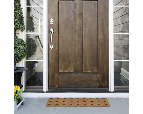 Fußmatte mit Willkommensgruß vor einer Haustür