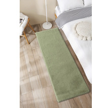 Grüner Teppich neben einem Bett auf einem Holzboden